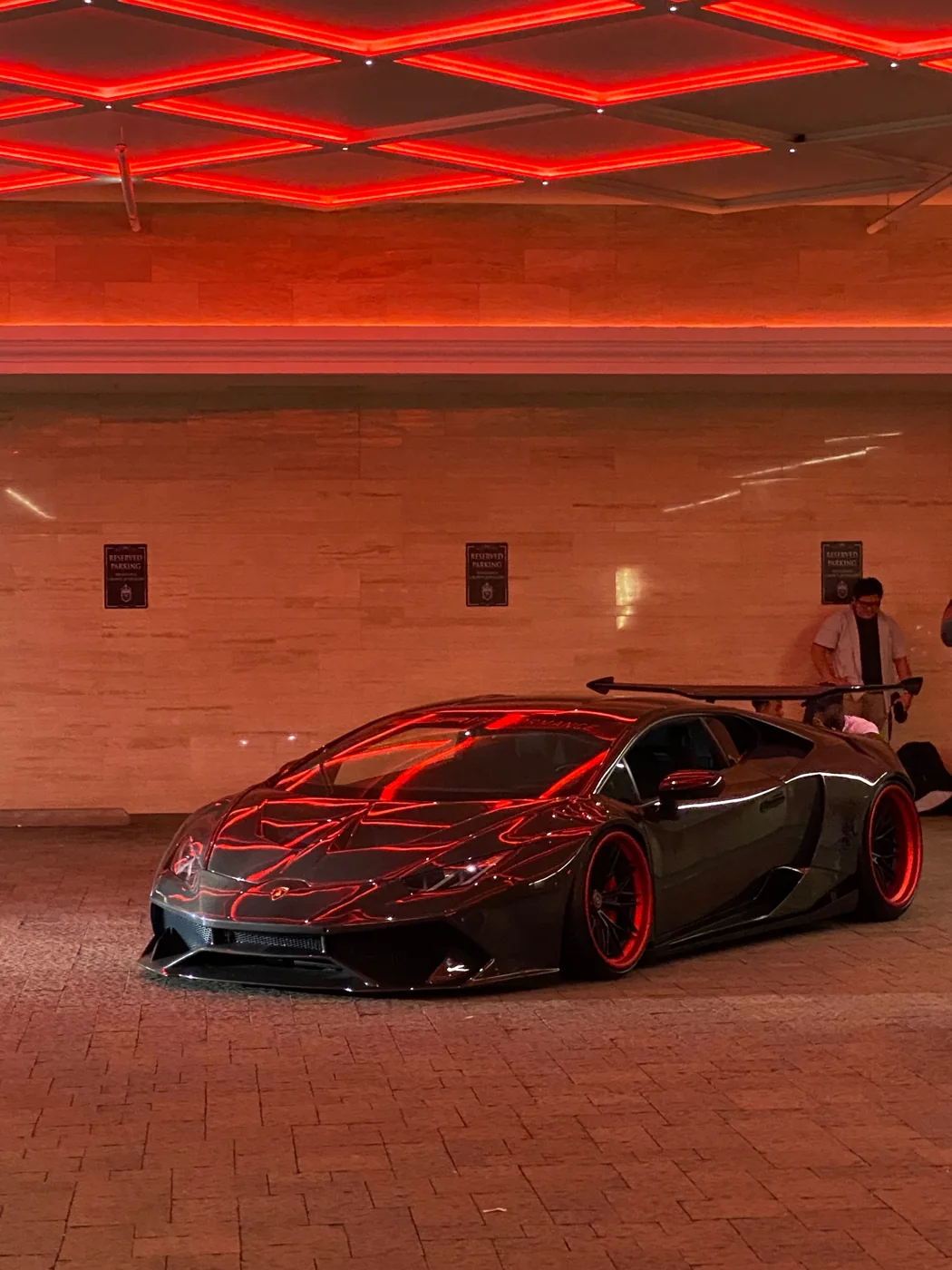 Black supercar in a garage lit with red light strips