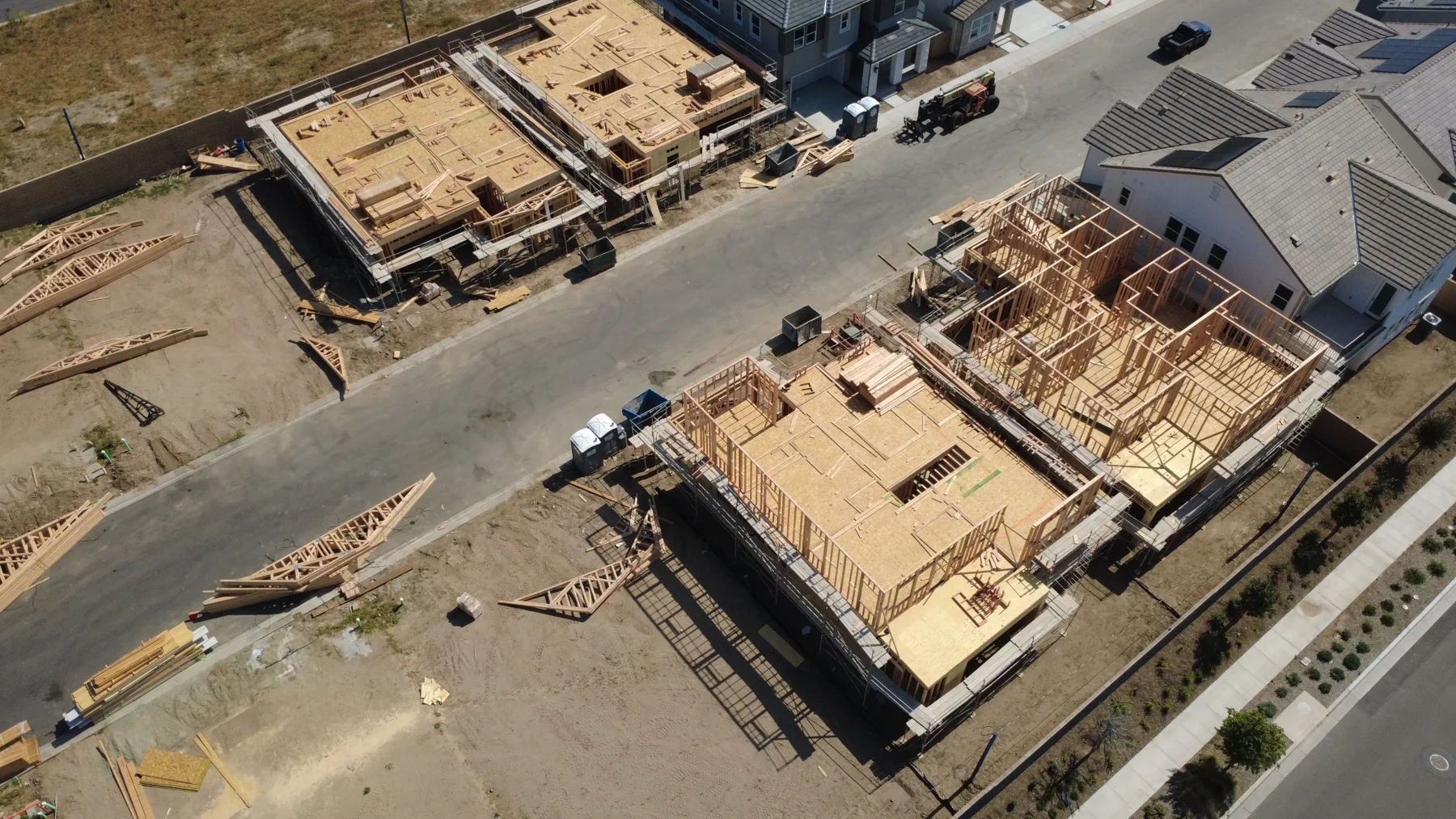 Overhead view of house lots under construction with framed houses and trusses staged on the ground