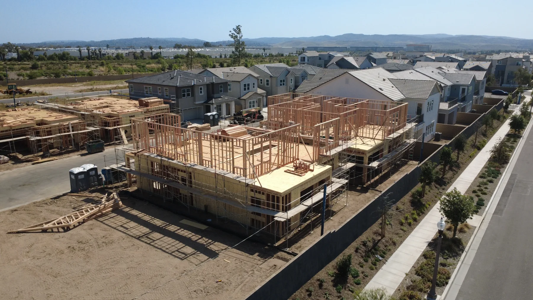 Two-story wood-framed house beside finished homes