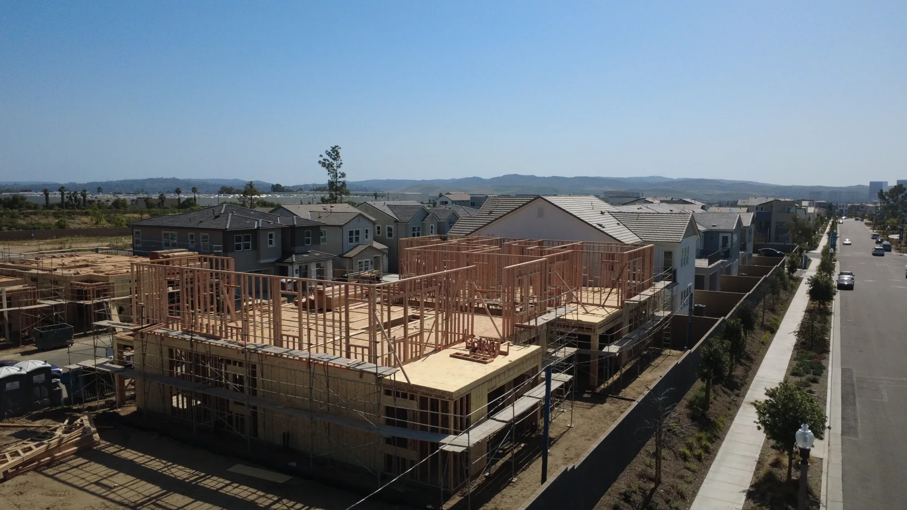 Wood-framed house under construction beside a new street